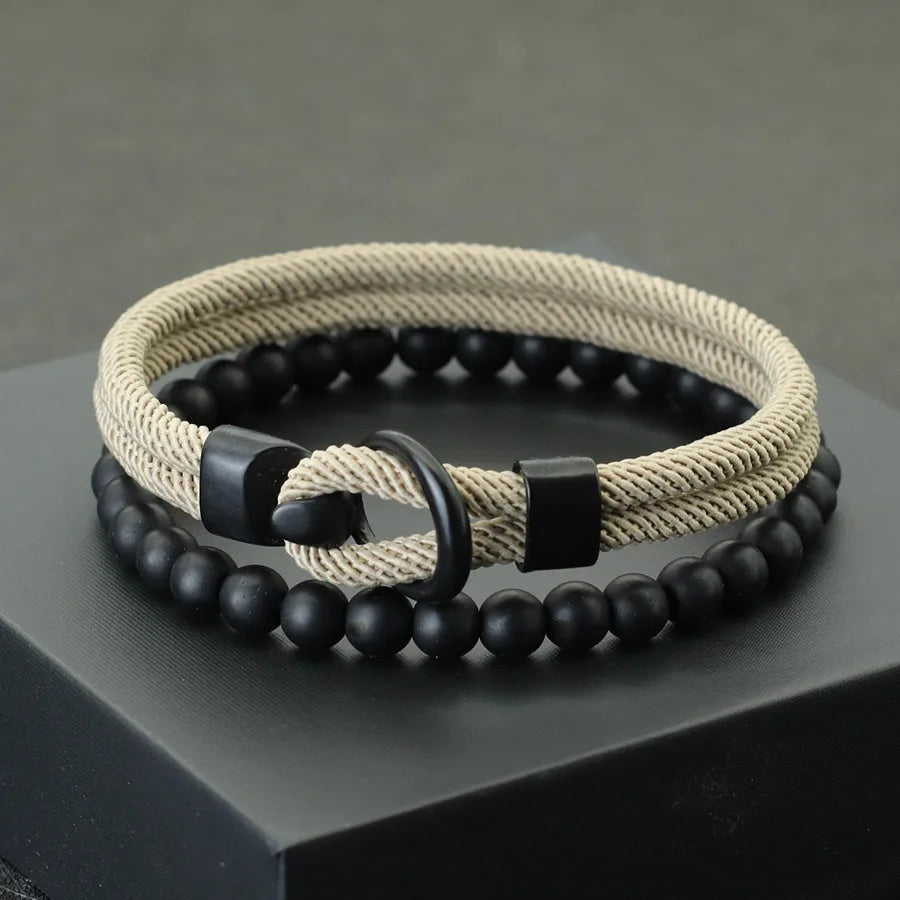 A red and black bracelet with a combination of smooth black beads and a textured red cord, displayed on a gray platform.