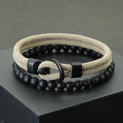 A red and black bracelet with a combination of smooth black beads and a textured red cord, displayed on a gray platform.