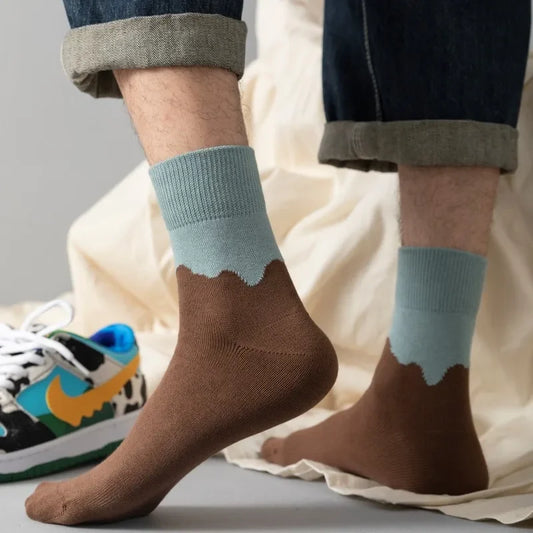 Person wearing brown and light blue gradient socks with a colorful sneaker in the background.