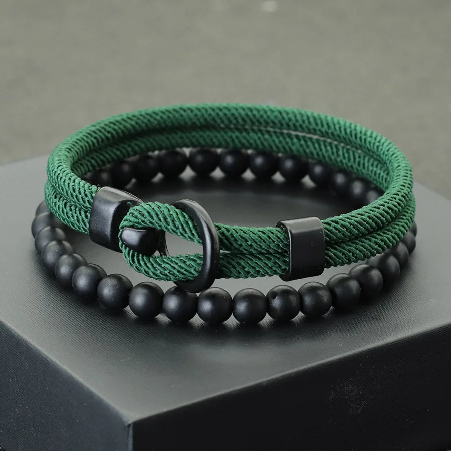 A red and black bracelet with a combination of smooth black beads and a textured red cord, displayed on a gray platform.
