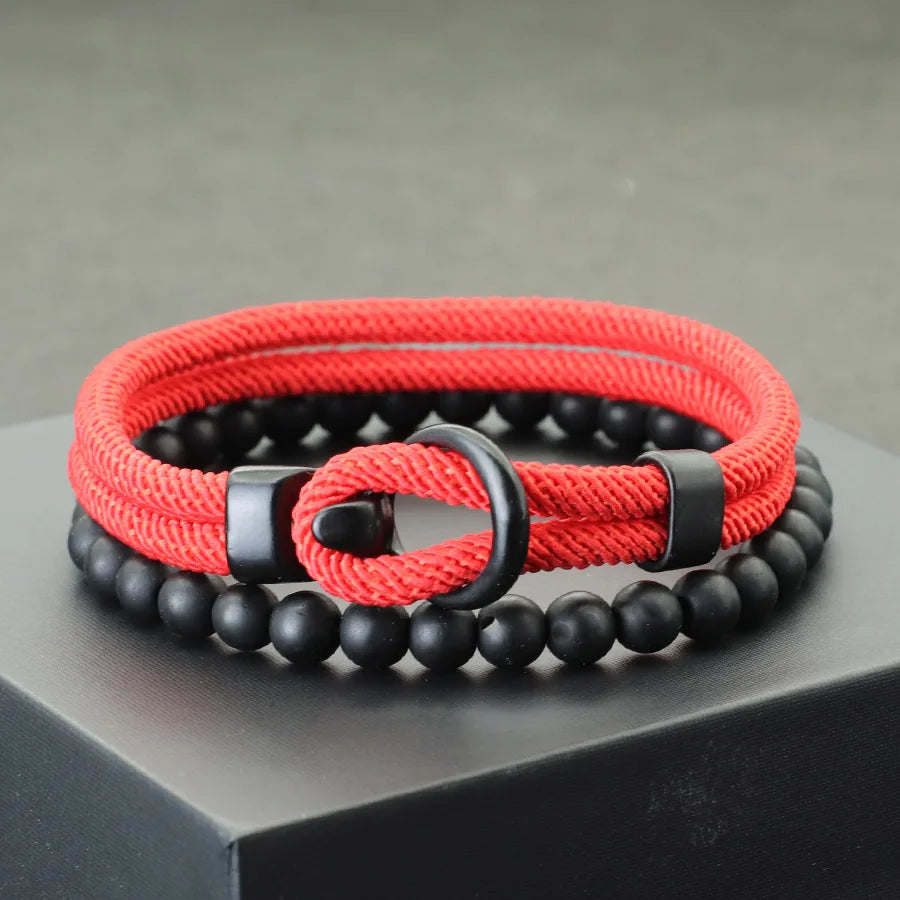 A red and black bracelet with a combination of smooth black beads and a textured red cord, displayed on a gray platform.