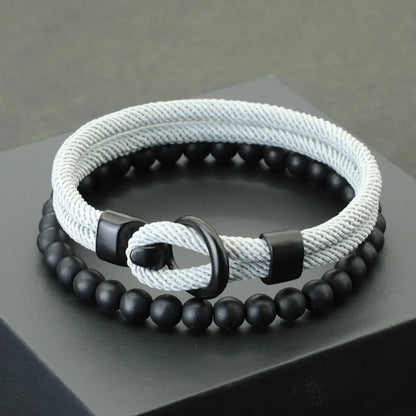 A red and black bracelet with a combination of smooth black beads and a textured red cord, displayed on a gray platform.